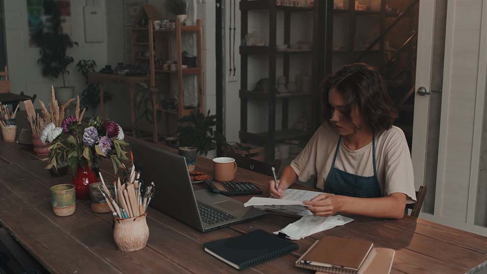 a woman calculation budget for her own pottery making business, she wanted to create something but doesn | Lumira Studio Video Production Hertfordshire't have a big budget, she trys to find out about How To Create Quality Video Content on a Budget