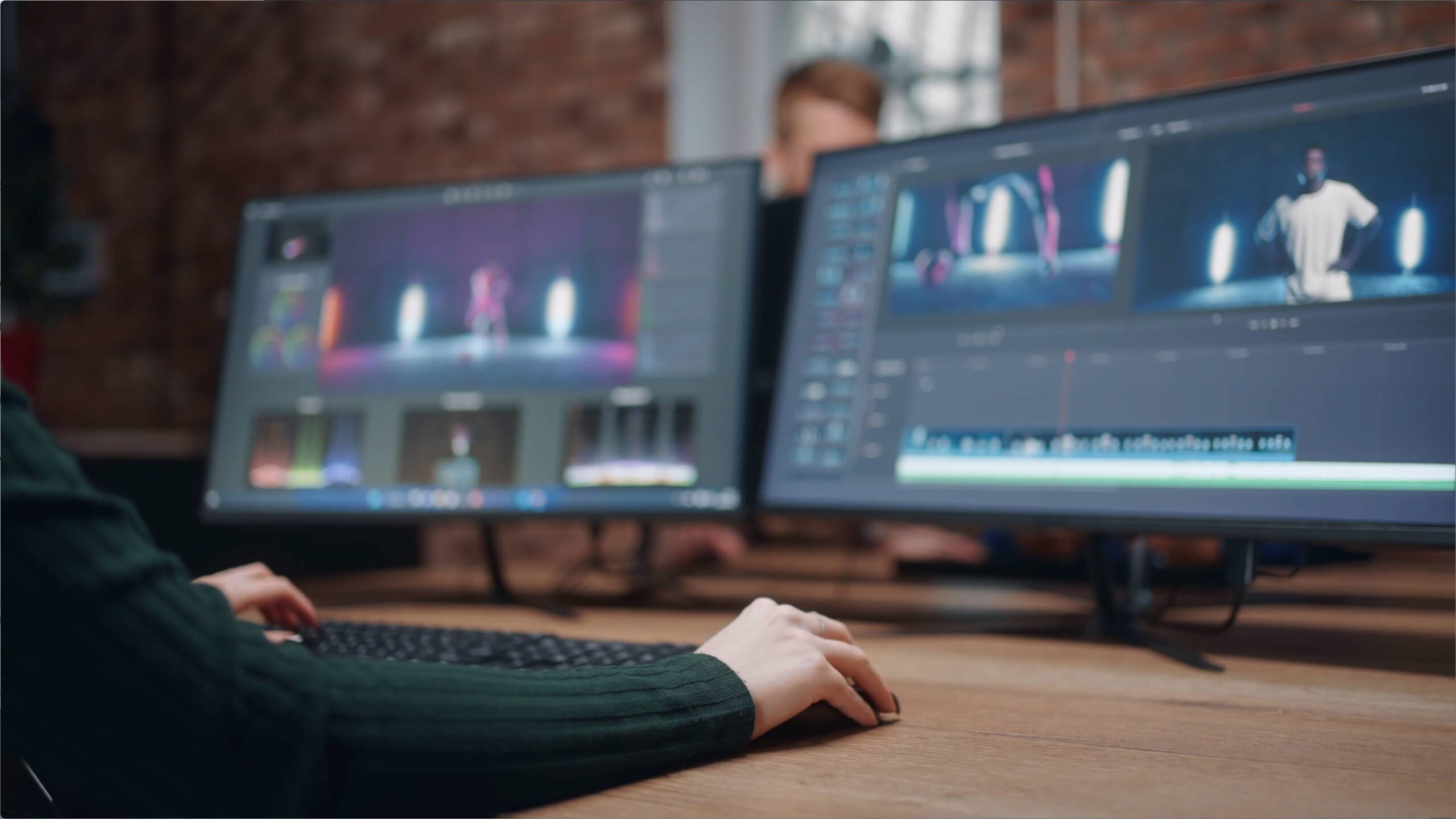 hands on keyboard in front of two monitors showing video editing software | Lumira Studio Video Production Hertfordshire