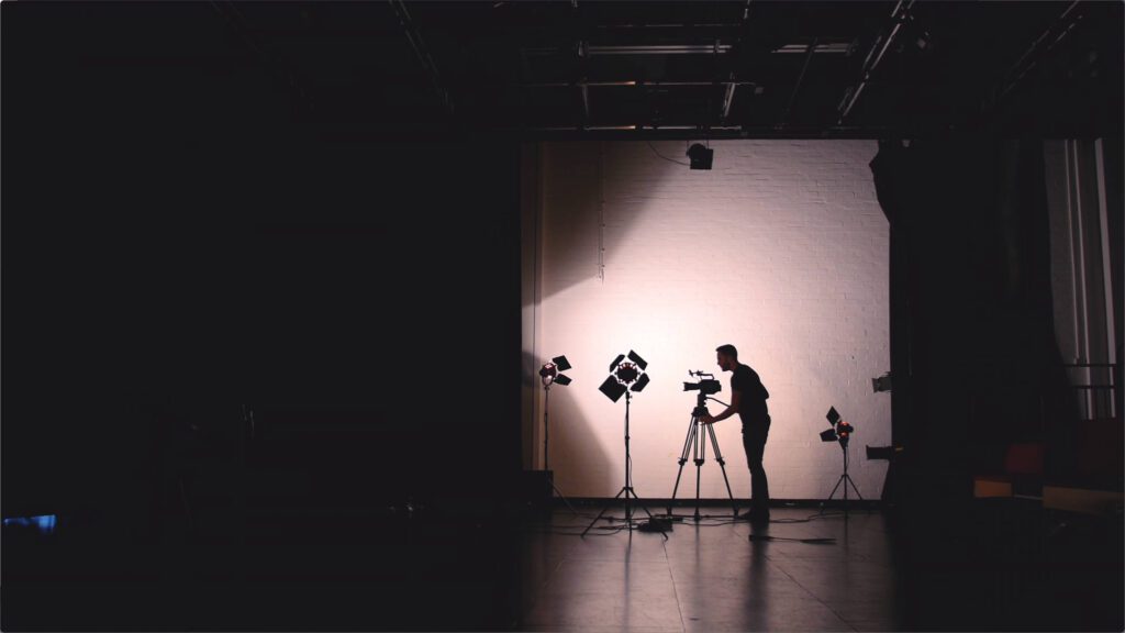 man silhouetted operating camera surrounded by three lights – Lumira Studio