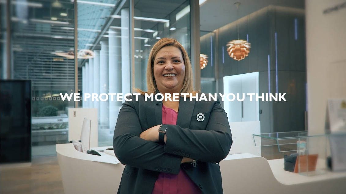 a female guard cross her arms smiling to the camera in a modern office building